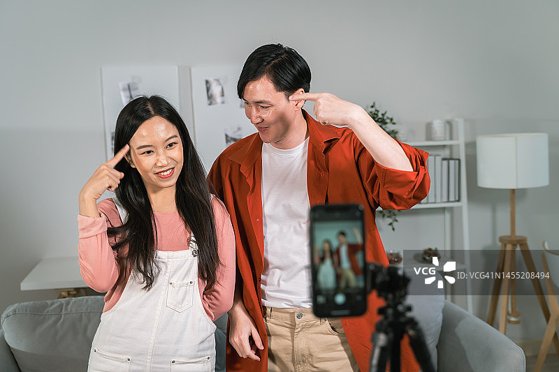 用手机拍摄舞蹈视频的亚洲年轻情侣图片素材