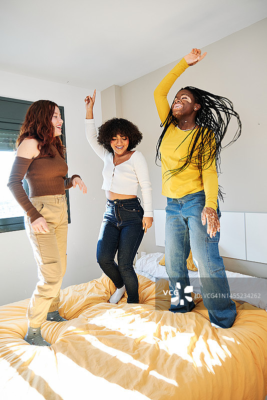 在床上跳舞的快乐多元文化女性图片素材