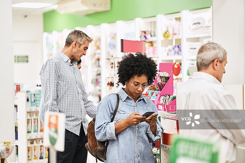 非洲裔女顾客在药房使用手机图片素材