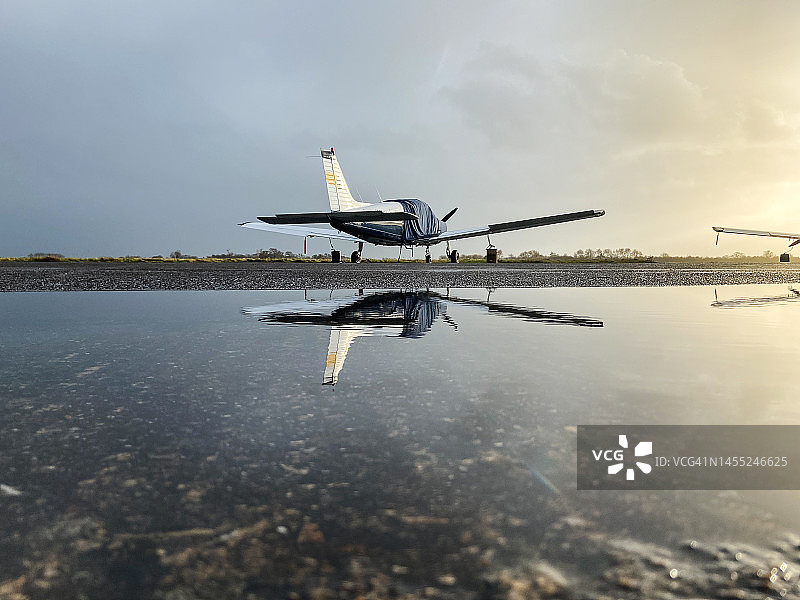 停放在日落时反射光芒的单引擎螺旋桨飞机图片素材