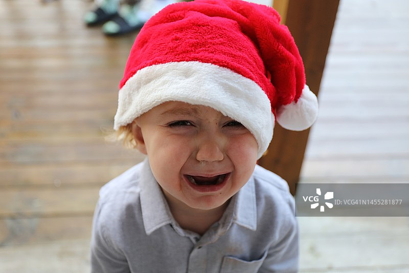 戴着圣诞帽看着镜头的哭泣男婴图片素材