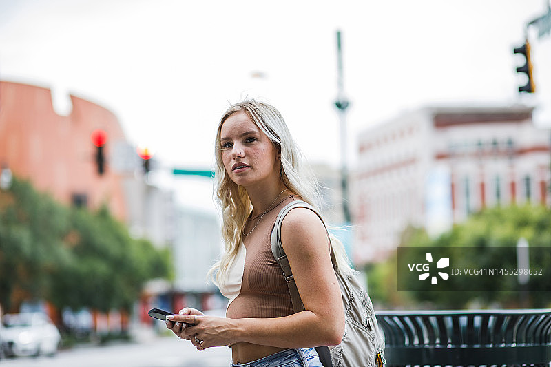 年轻女子站在人行道上等待出租车图片素材