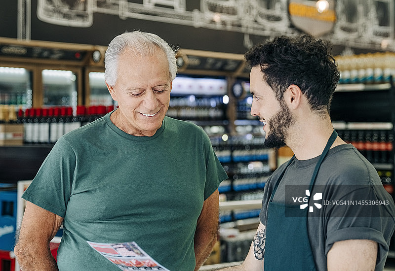 年轻的男售货员在杂货店帮助年长的顾客图片素材