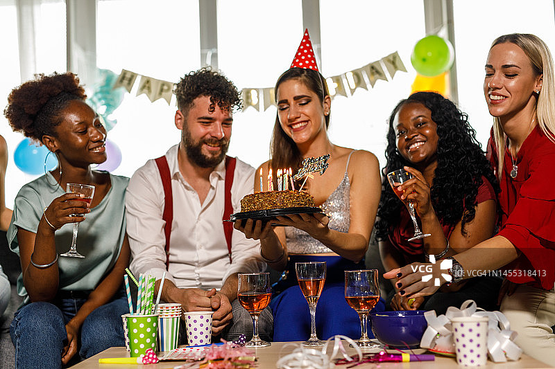一群快乐的闺蜜为她们的男性朋友唱“生日快乐”歌，同时举着蛋糕图片素材