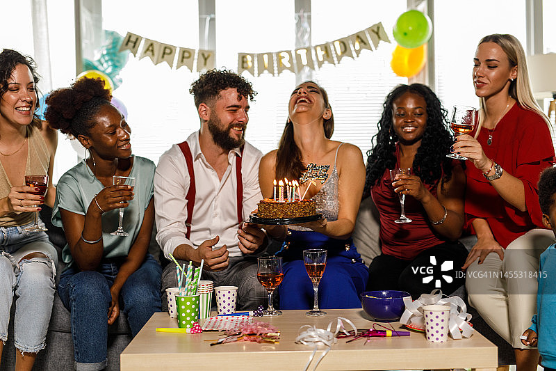 一群快乐的闺蜜为她们的男性朋友唱“生日快乐”歌，同时举着蛋糕图片素材