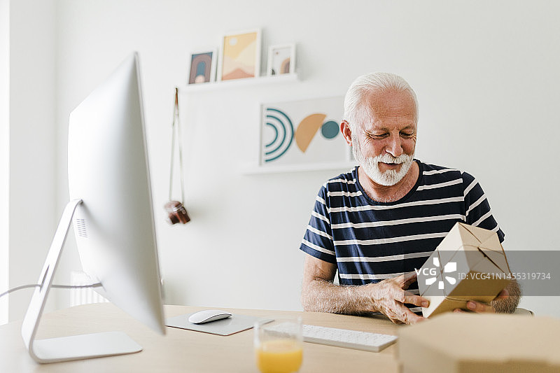 在网上商店工作的老年男子。在Covid-19大流行期间远程办公。小企业主图片素材