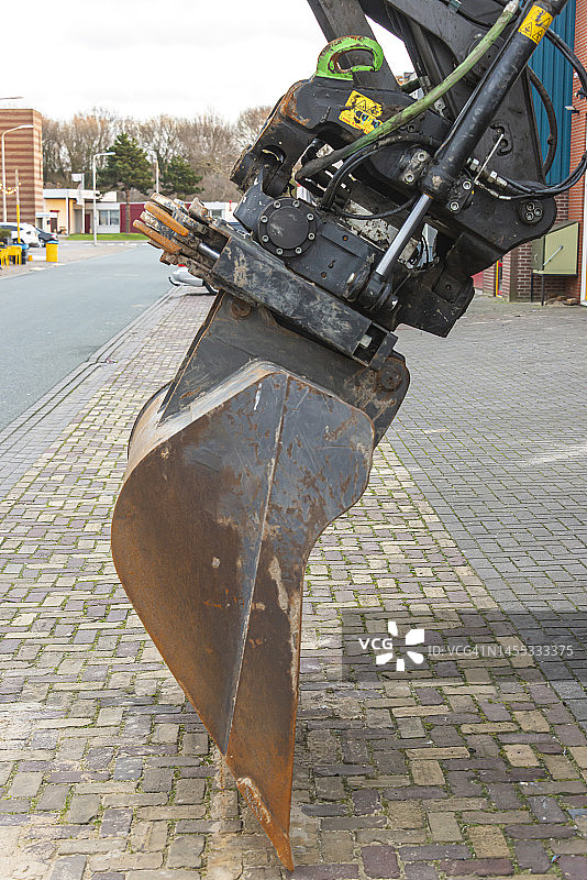 垂直停放在地面的液压铲斗图片素材