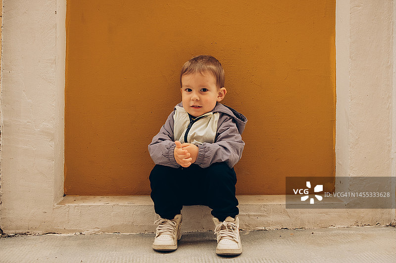 坐在黄色背景街道上的快乐儿童图片素材