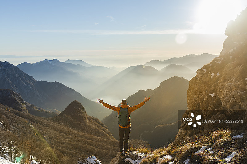 在山上张开双臂的快乐徒步旅行者图片素材
