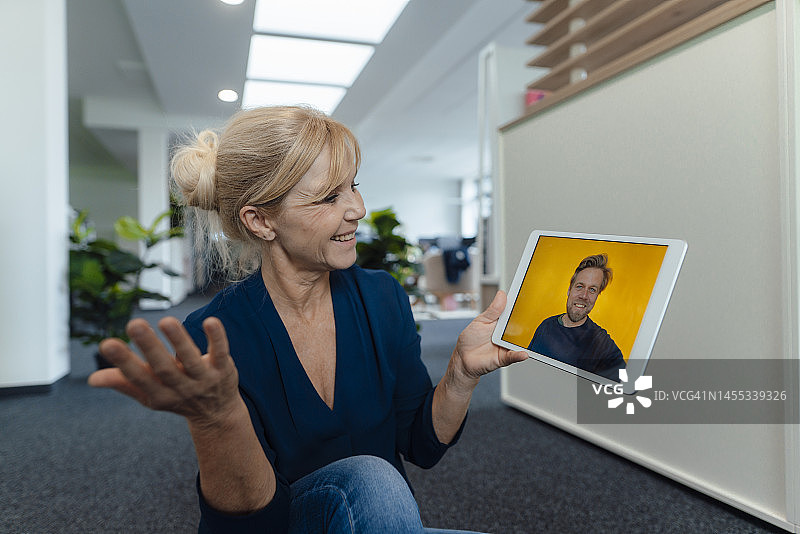 微笑的女商人通过平板电脑在办公室进行视频通话图片素材
