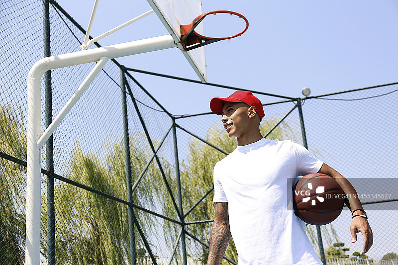 阳光明媚的日子里手持篮球的年轻男人图片素材