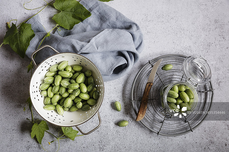 沥水篮和罐子里的新鲜迷你黄瓜图片素材