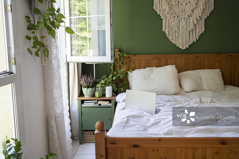 卧室里床上方的马卡拉梅挂毯和笔记本电脑图片素材