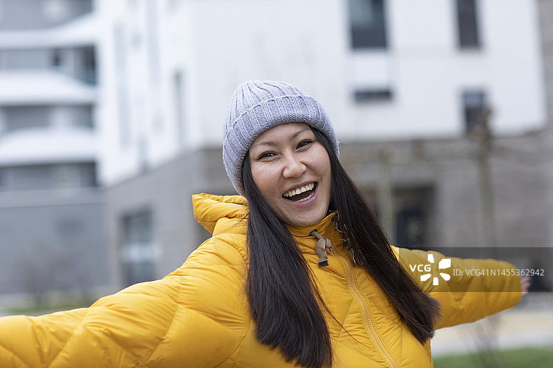 快乐的女人戴着针织帽站着，张开双臂图片素材