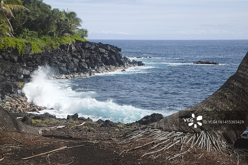 海浪在黑色熔岩岩石海岸线的海湾中撞击图片素材