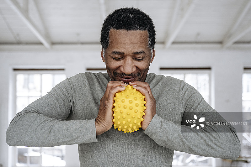 快乐的男人在家挤压黄色压力球图片素材
