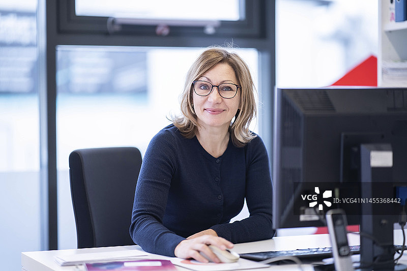 笑容满面的女人坐在桌前使用电脑图片素材