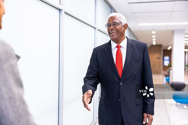 年长的黑人商人和年轻女性在走廊里握手图片素材
