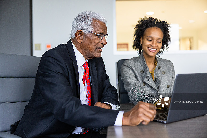 老年黑人商人和妇女在会议室使用笔记本电脑图片素材