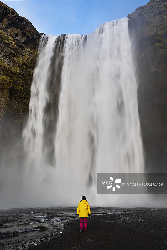 秋日，在冰岛南部地区欣赏斯科加瀑布的女孩图片素材