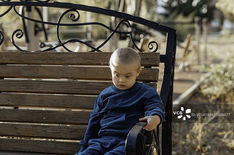 患有唐氏综合征的金发可爱男孩在公园散步图片素材