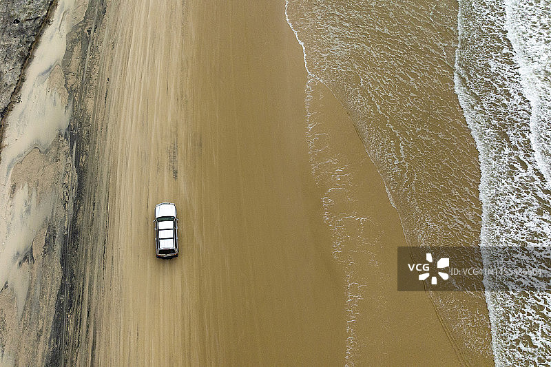 停在海滩道路上的SUV的鸟瞰图图片素材