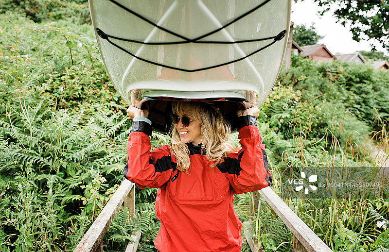 快乐女人头顶皮划艇去海滩图片素材