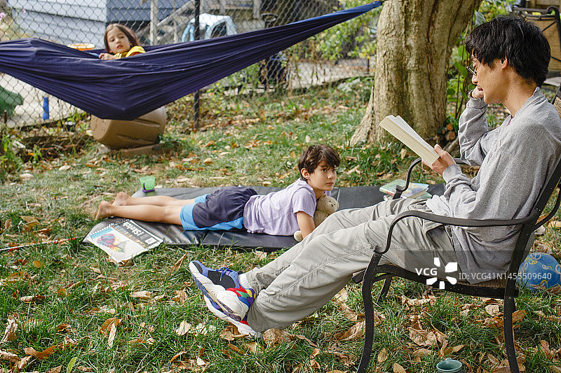 父亲在后院户外给孩子们读书图片素材