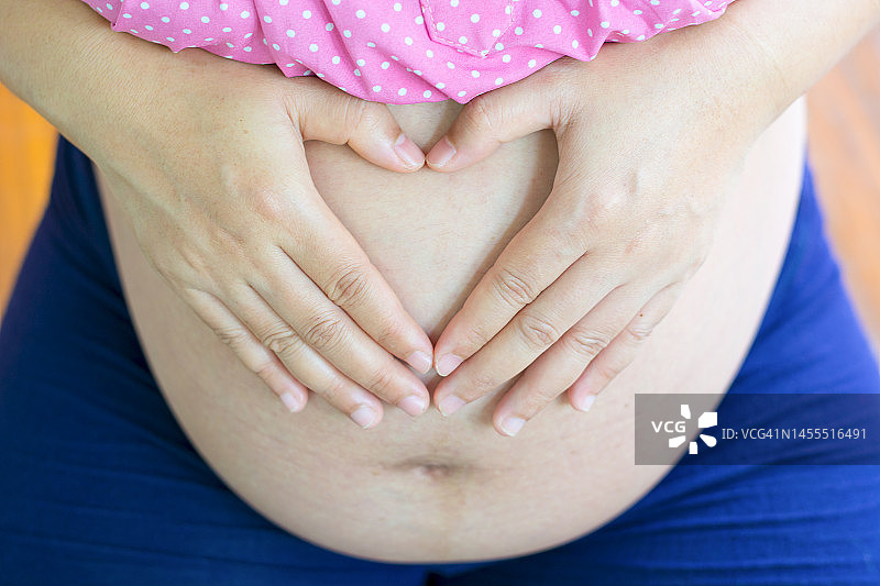 孕妇在家用手在腹部做心形图片素材