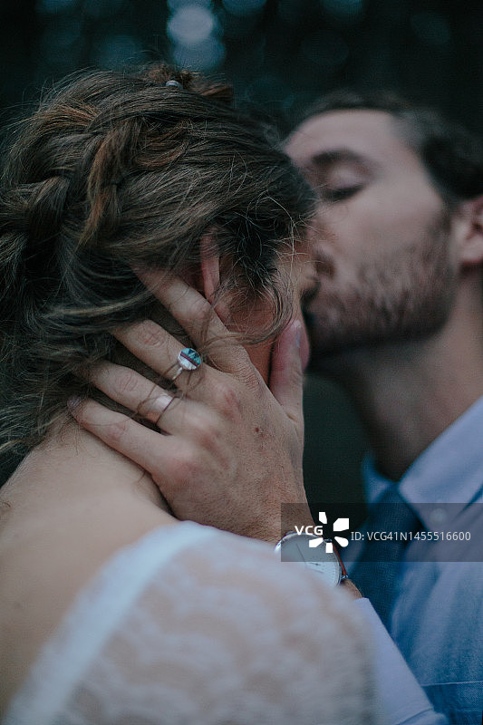 新郎戴着部落戒指在加利福尼亚州森林中亲吻新娘图片素材