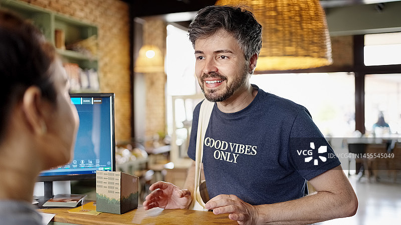 快乐的男顾客在柜台向女咖啡师点餐图片素材