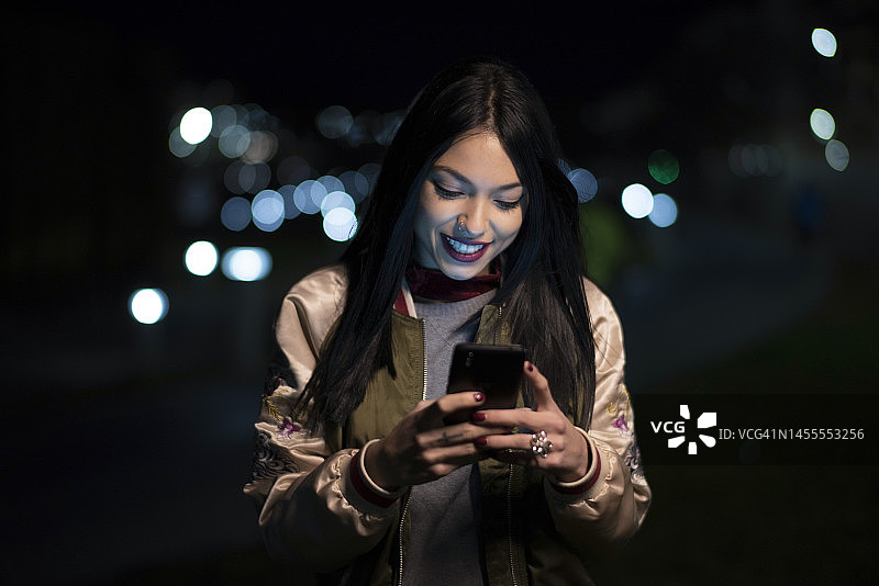 夜晚在城市里看手机的女人图片素材