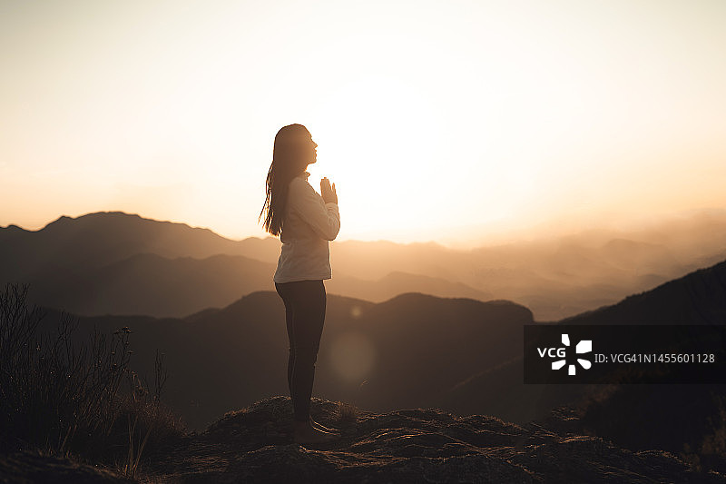 女子在山中日落时冥想图片素材
