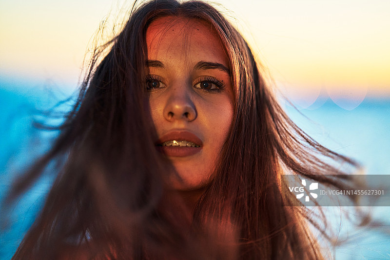 面带微笑注视镜头的漂亮女人，展示被风吹起的秀发（正面视角）图片素材