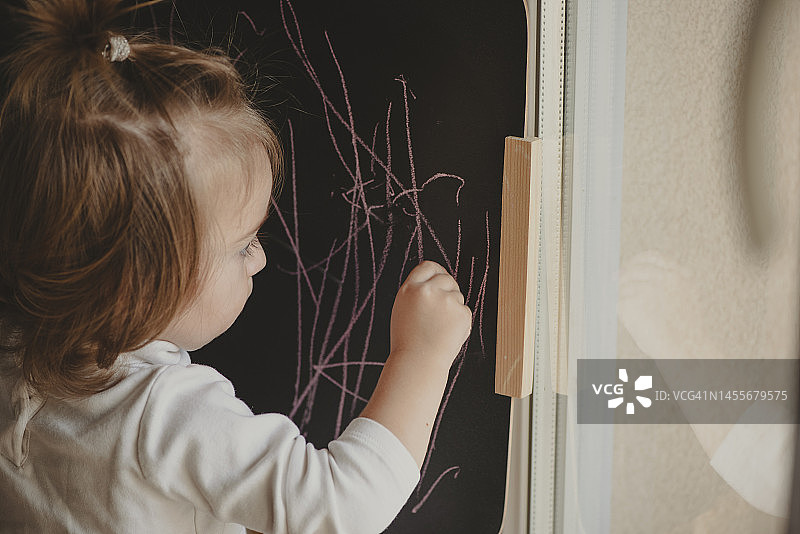 在黑板上写字绘画的女婴图片素材