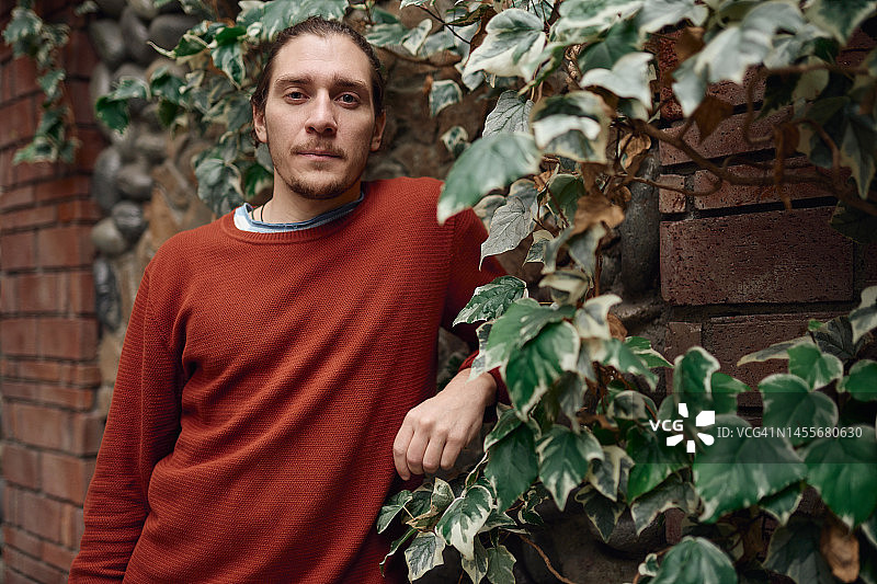 站在常春藤石墙旁的年轻男子肖像图片素材
