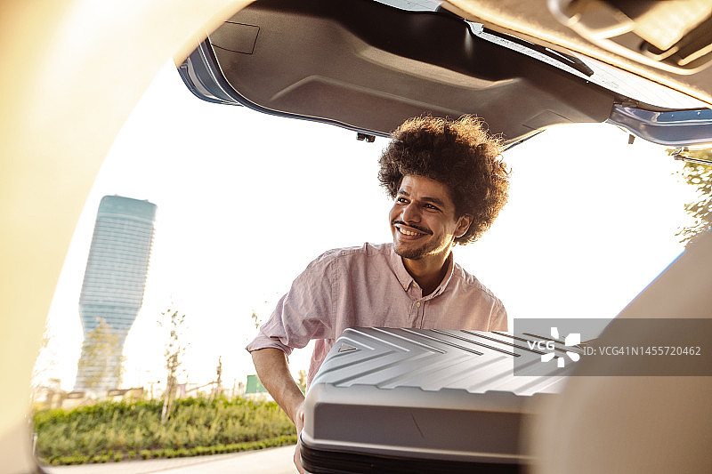 年轻人将行李装入汽车后备箱图片素材