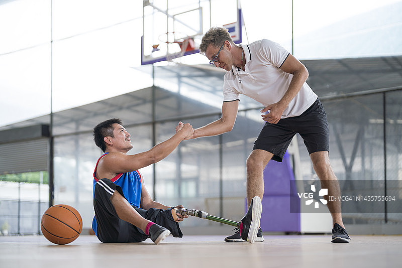 教练在篮球比赛中帮助安装假肢的截肢者图片素材
