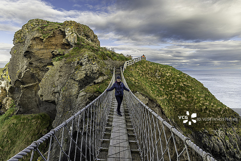 一位游客兴奋地走过卡里克索桥，前往英国北爱尔兰安特里姆郡的卡里克雷德岛图片素材