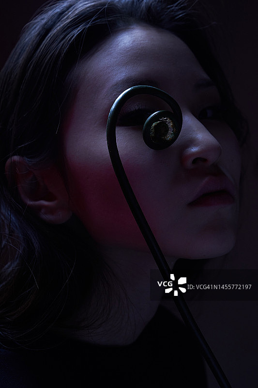 亚洲女性面部背景上的罕见乌卢赫蕨类植物茎，特写肖像图片素材