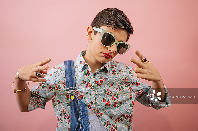 戴墨镜的年轻人在粉色背景上展现少女感，青春期性别认知困惑图片素材