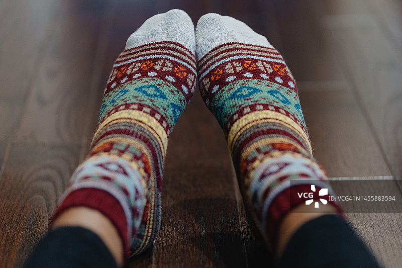女人坐在硬木地板上，穿着彩色羊毛袜图片素材