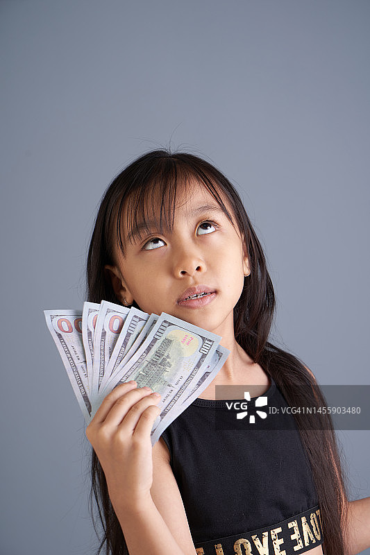 快乐的亚洲女孩拿着美元钞票做梦图片素材