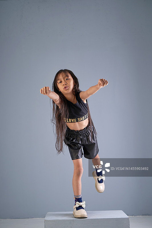 在灰色背景下做出起飞手势的快乐女孩图片素材