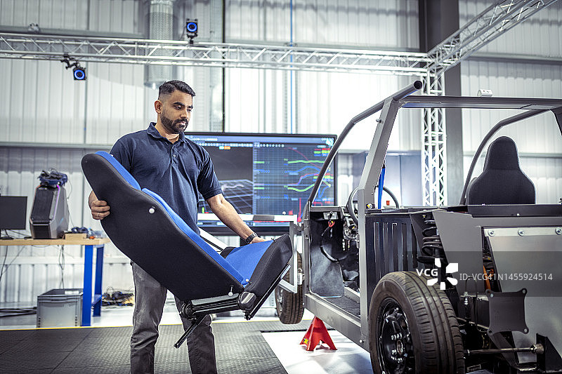 英国伯恩利：车辆研究机构中搬运汽车座椅的工人图片素材