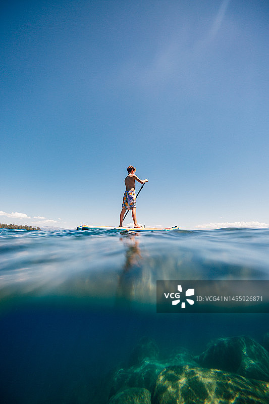 美国加利福尼亚州太浩湖上男孩桨板运动的低角度视图图片素材