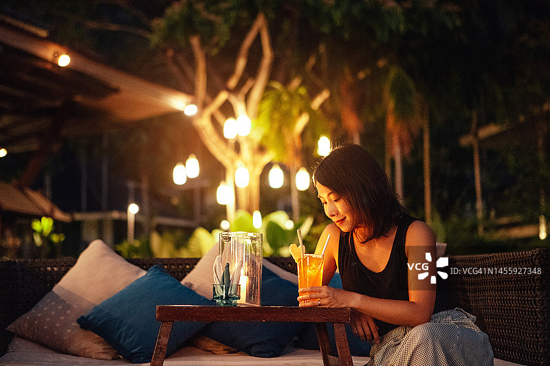 年轻的亚洲女性在豪华花园酒吧放松身心图片素材