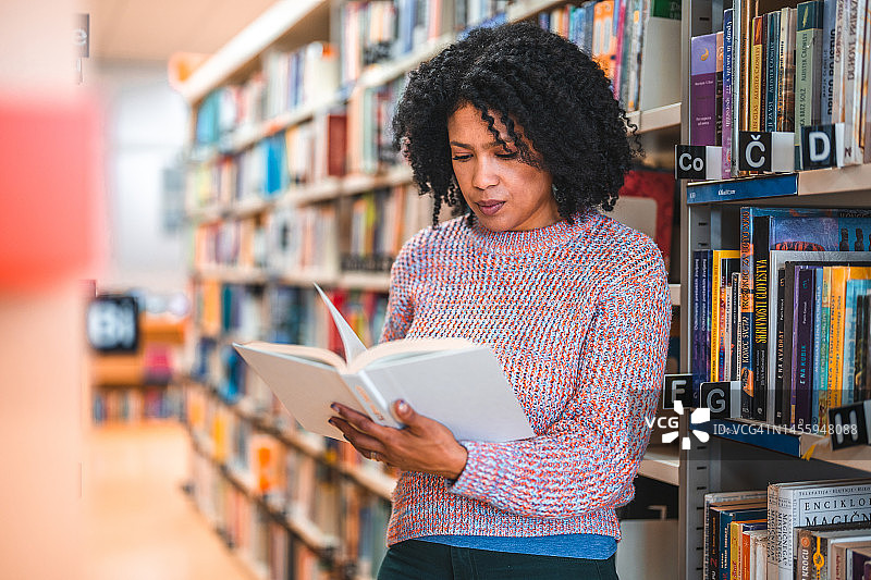 翻阅书籍的30多岁西班牙裔女性图片素材