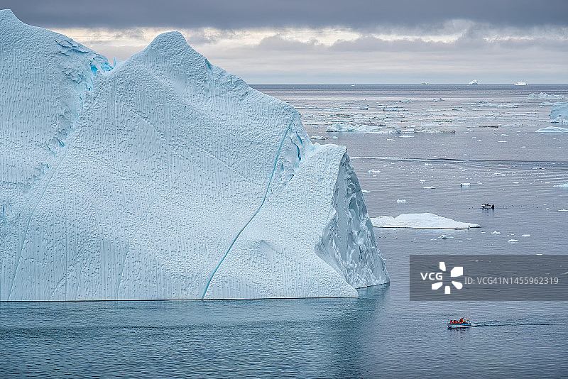 格陵兰伊卢利萨特冰峡湾的冰山间航行的船只图片素材