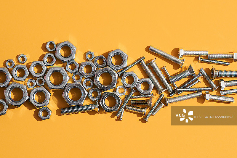 许多黄色背景上的六角螺母和螺丝图片素材